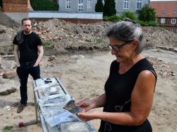 Ines Beilke-Voigt zeigt einen Keramikrest, der auf der Baustelle an der Burgstraße gefunden wurde. Foto: Landkreis Prignitz