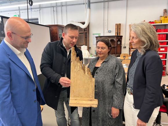 Gordon Thalmann zeigt ein Teil des zerstörten Altars aus der Kirche Klein Linde und erklärt Landrat Christian Müller, Professorin Angelika Rauch und der Präsidentin Prof. Dr. Eva Schmitt-Rodermund die einzelnen Schritte der Restaurierung. (Fotonachweis: Landkreis Prignitz)